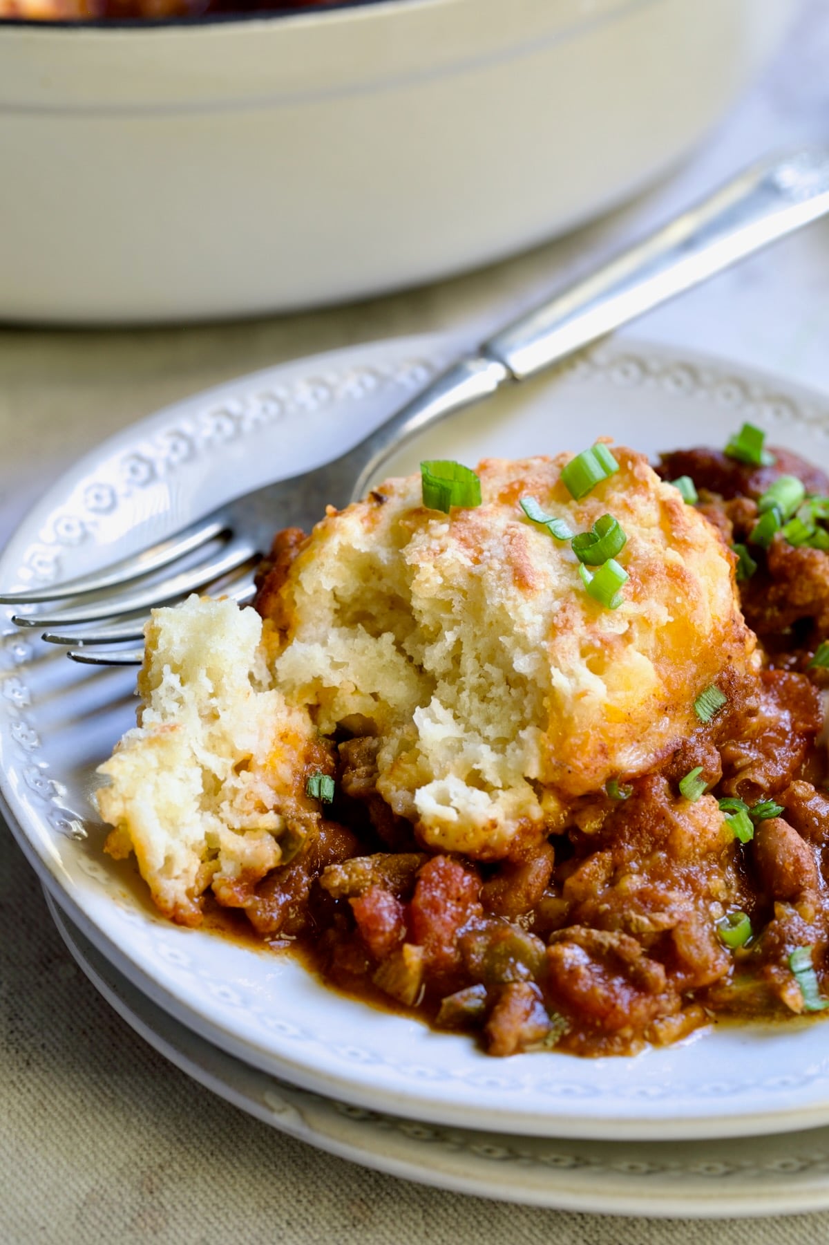 One serving of Biscuit-Topped Turkey Skillet Chili on small white plate with fork.