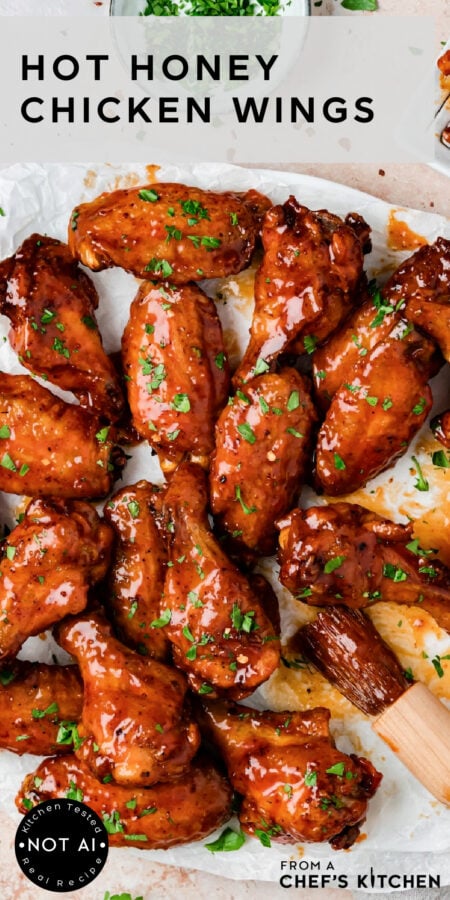 Pinterest graphic for Hot Honey Chicken Wings showing them glazed on a parchment paper lined platter.