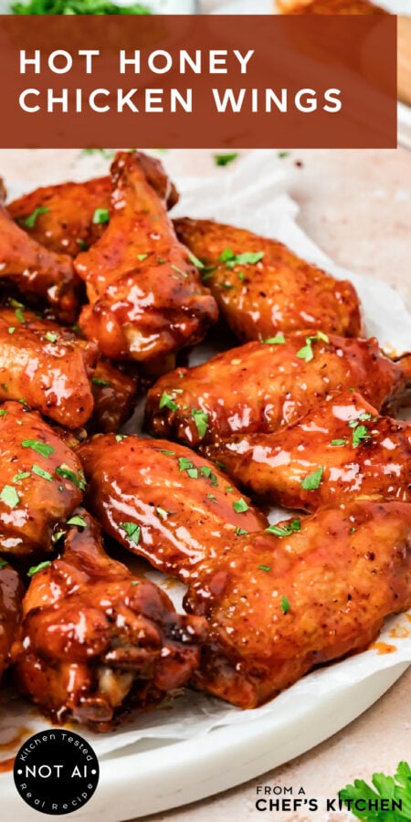 Pinterest graphic for Hot Honey Chicken Wings showing them glazed on a parchment paper lined platter.