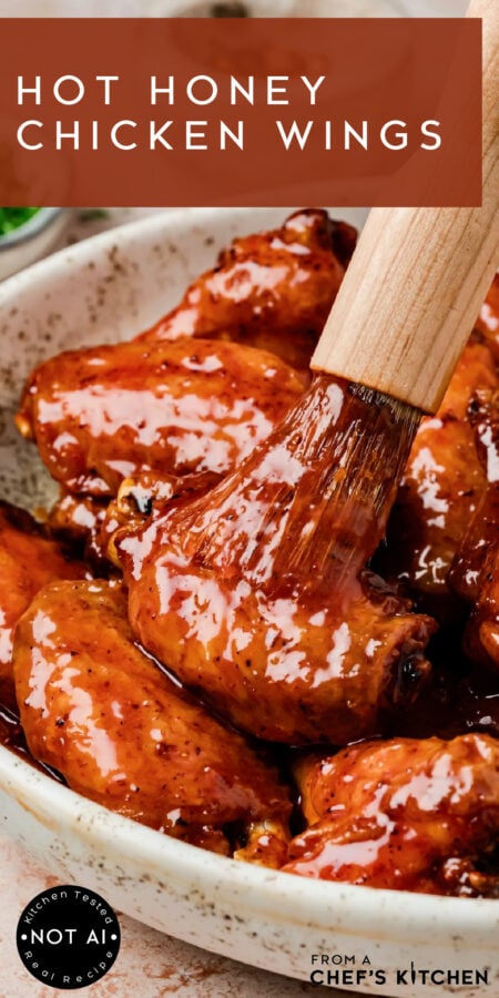 Pinterest graphic for Hot Honey Chicken Wings showing them being glazed with a wooden basting brush.