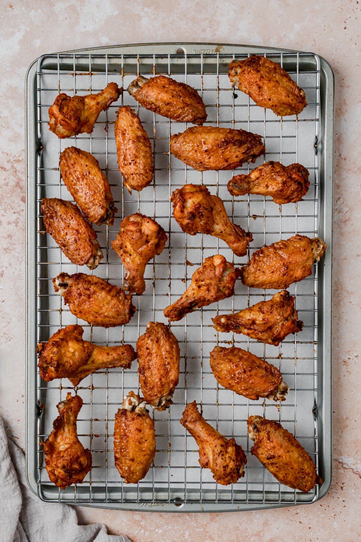 Wings on rack-lined rimmed baking sheet after being baked.