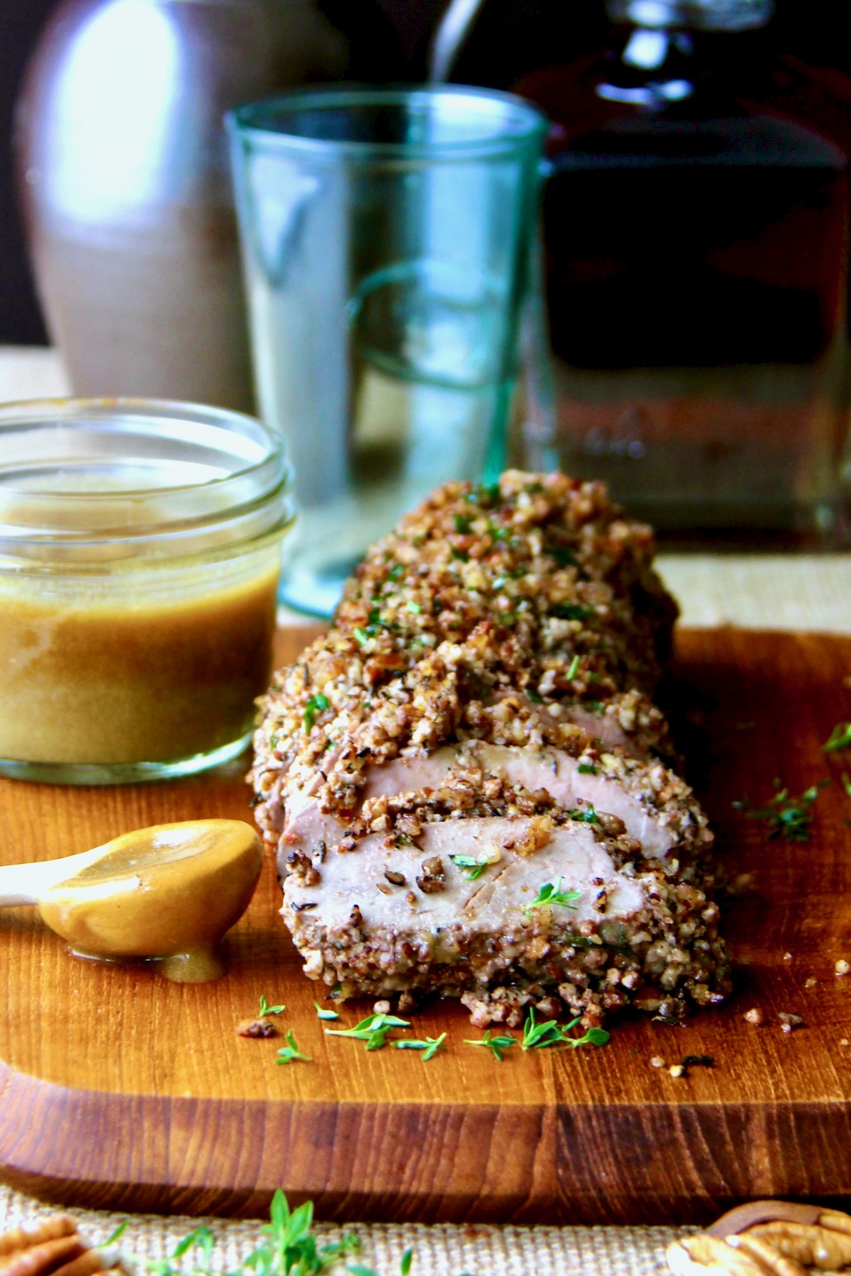Pecan-Crusted Pork Tenderloin with Bourbon - Mustard Sauce on wood cutting board.