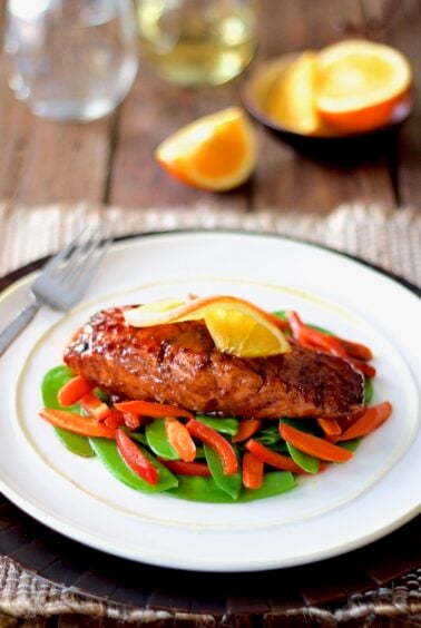 Pomegranate and Orange-Glazed Salmon with Stir-Fried Vegetables on white plate.