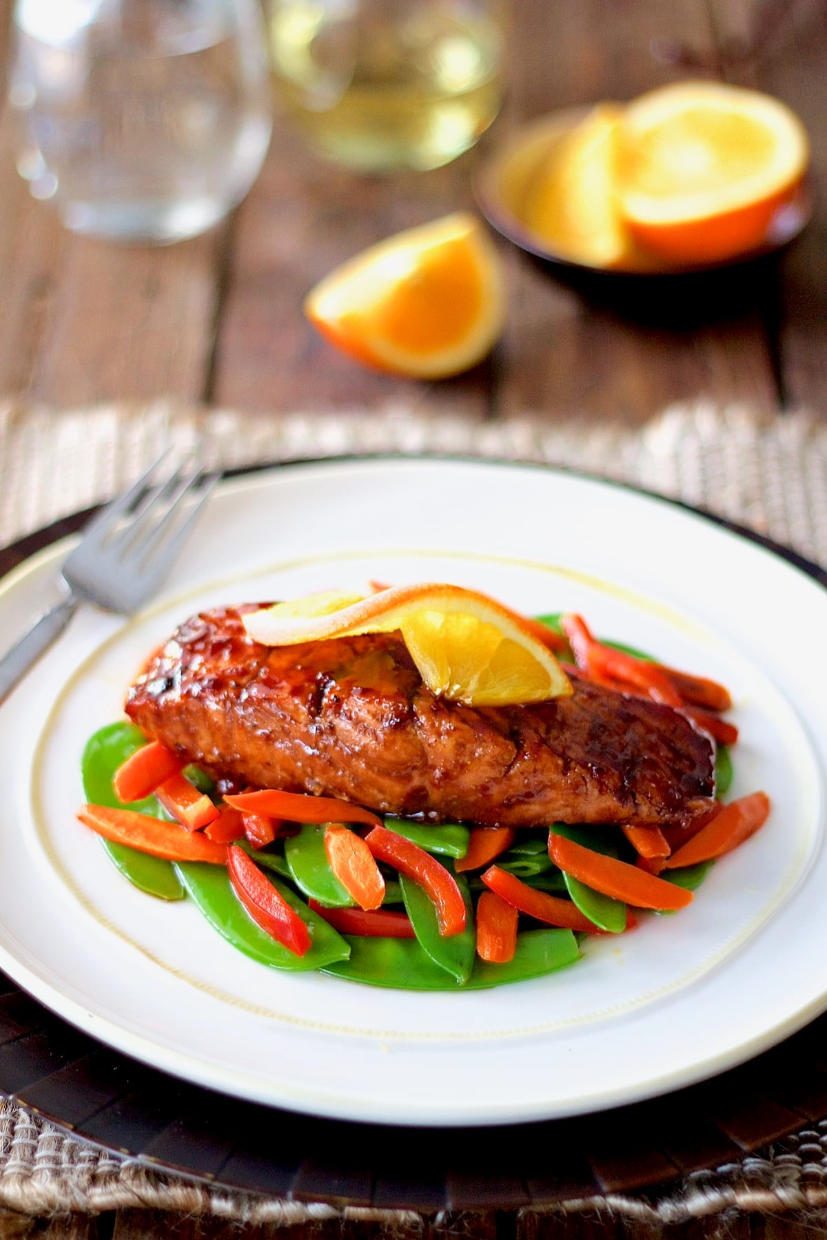 Pomegranate and Orange-Glazed Salmon with Stir-Fried Vegetables on white plate.