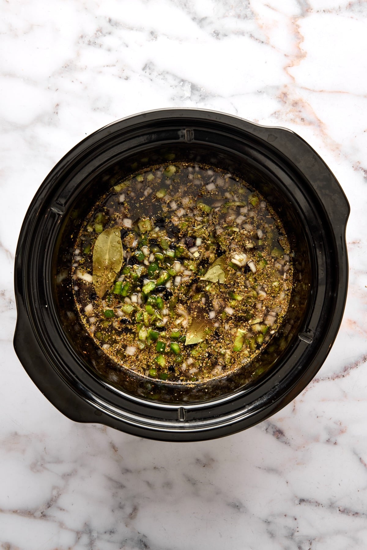 Ingredients for Slow Cooker Black Bean Soup in slow cooker before being stirred together before being cooked.