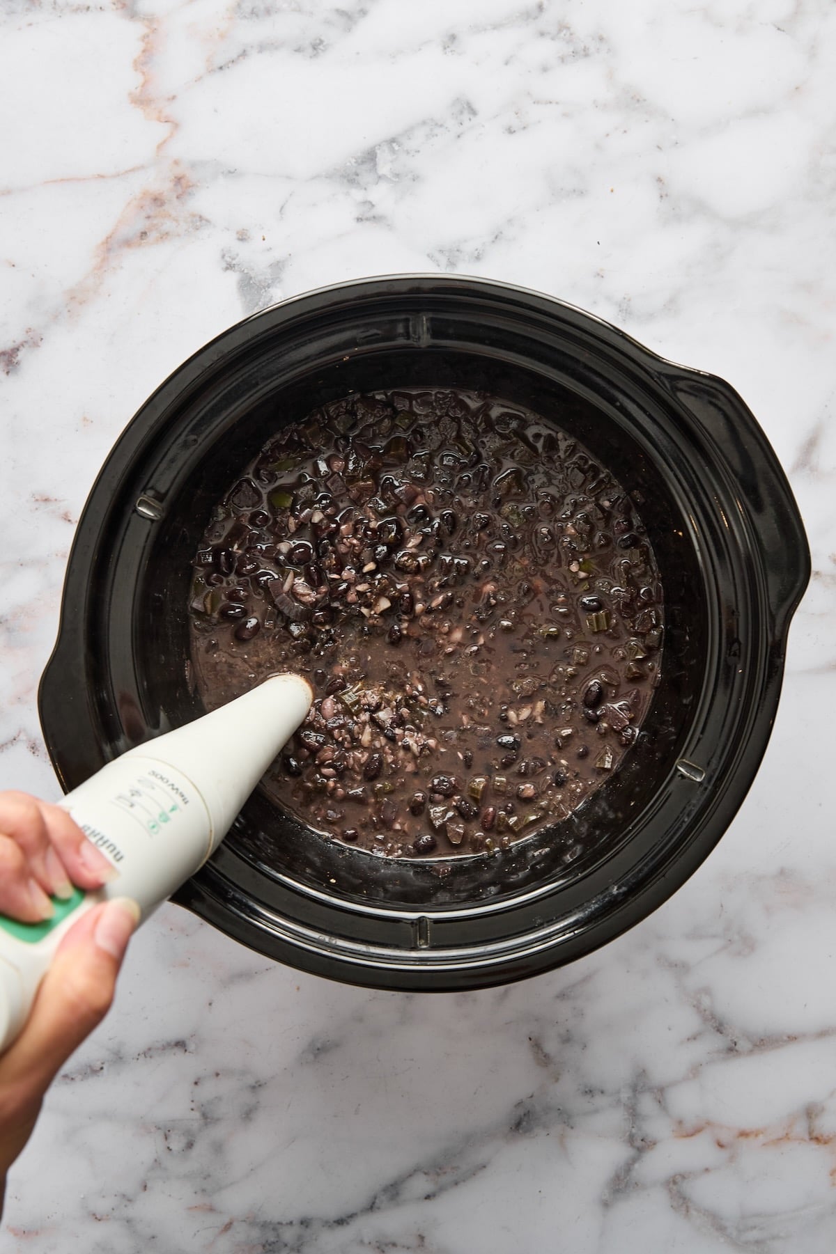 Slow Cooker Black Bean Soup in slow cooker after being cooked being pureed with an immersion blender.