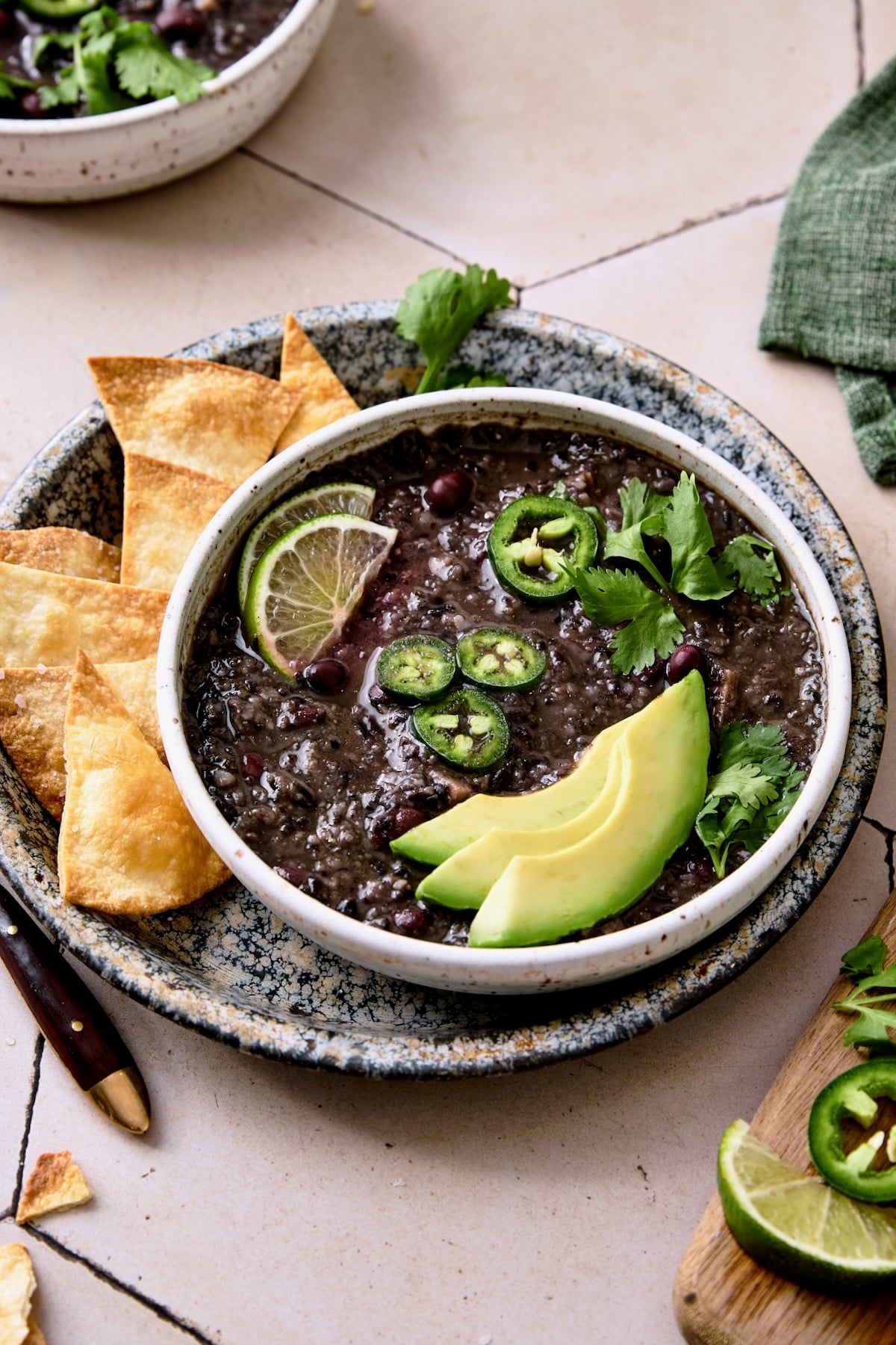 Slow Cooker Black Bean Soup on speckled plate with tortilla chips.