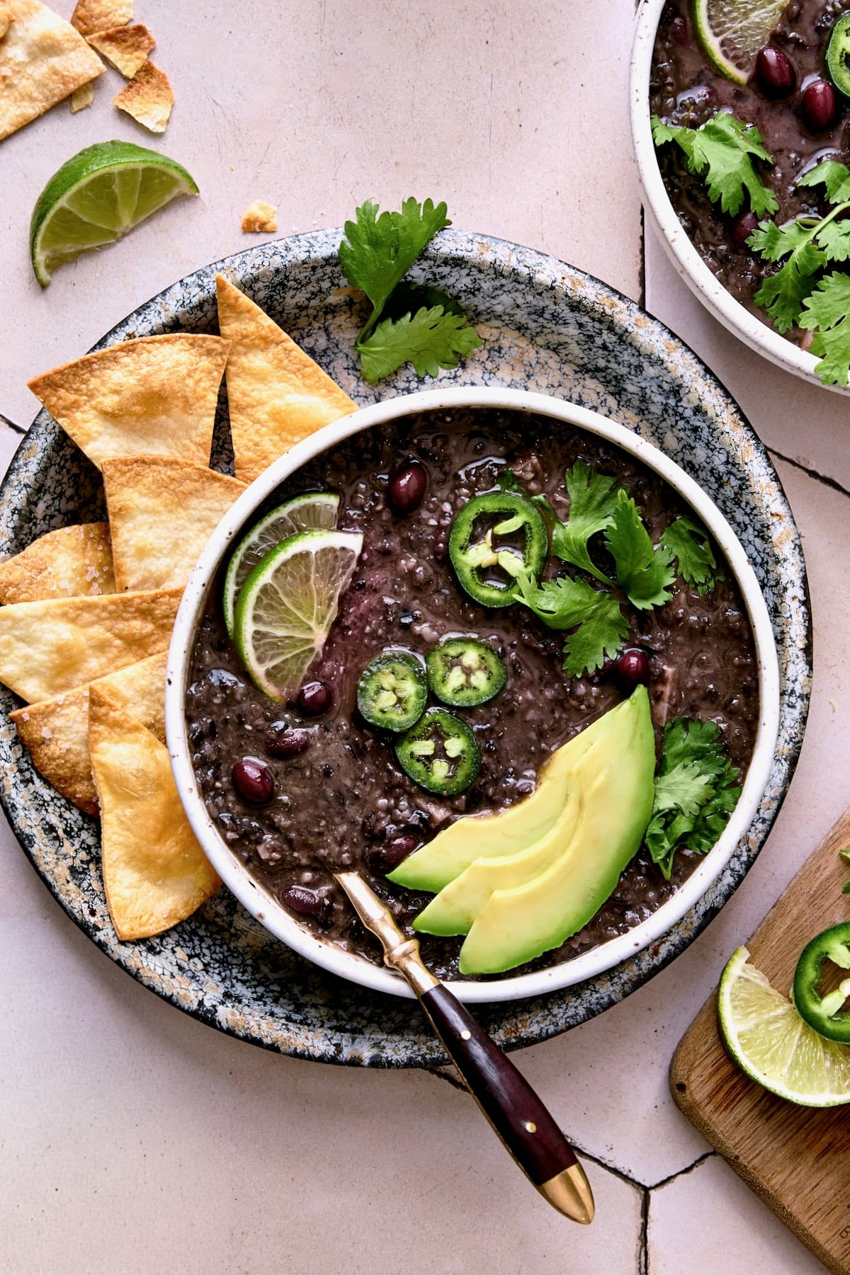 Slow Cooker Black Bean Soup on speckled plate with tortilla chips.