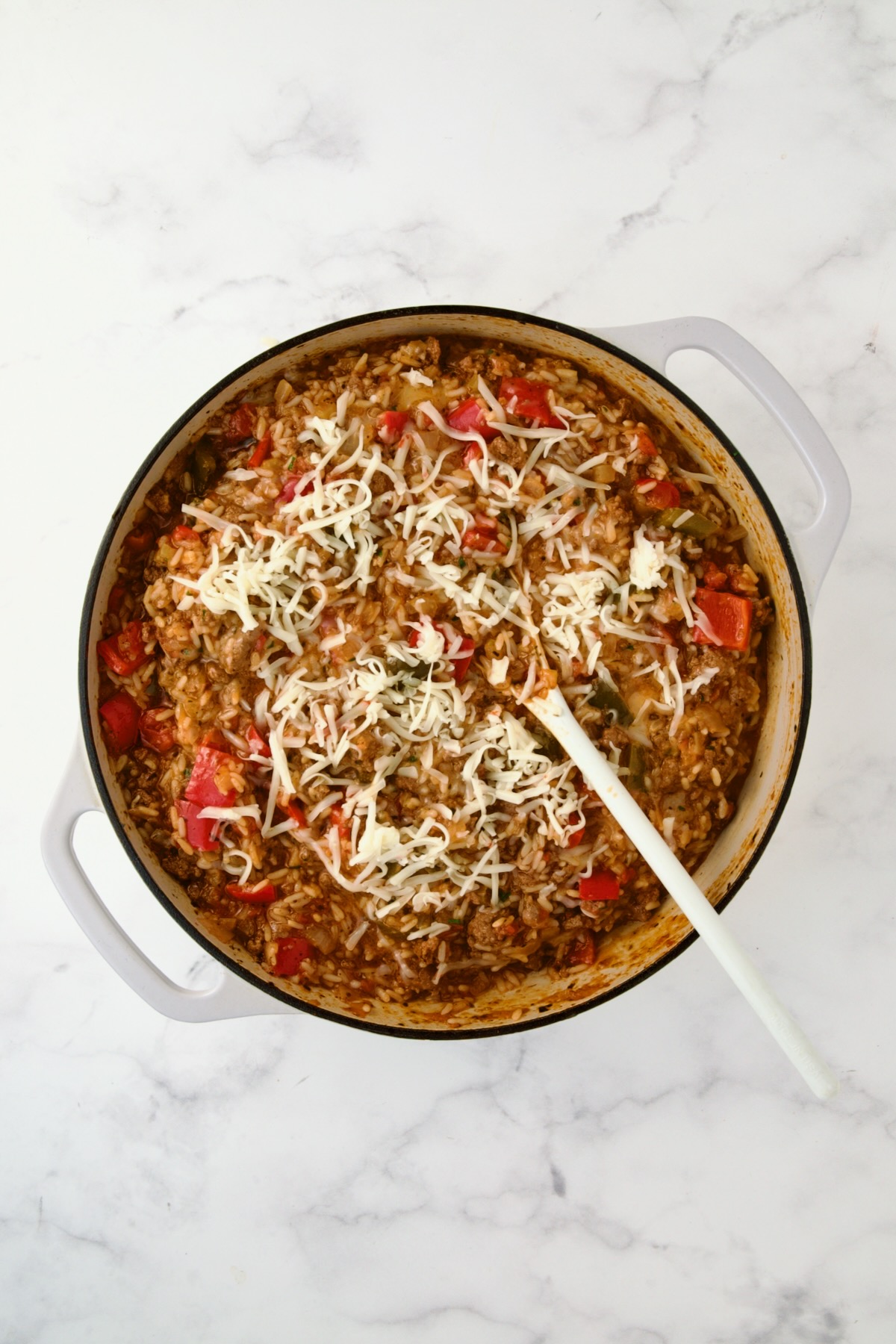 Cheese stirred into finished dish in white enamel cast iron skillet.