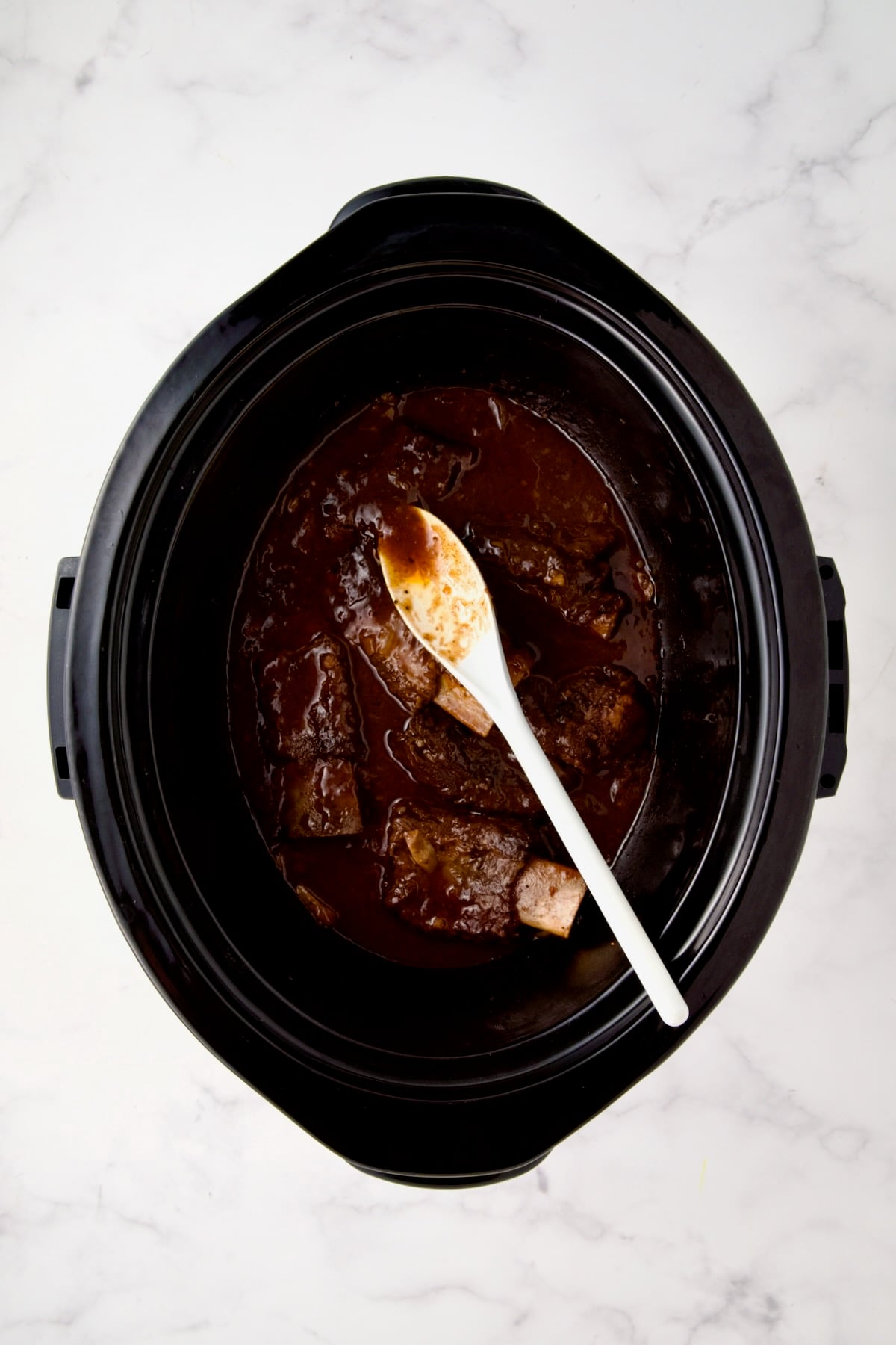 Beef ribs in slow cooker after being thickened.