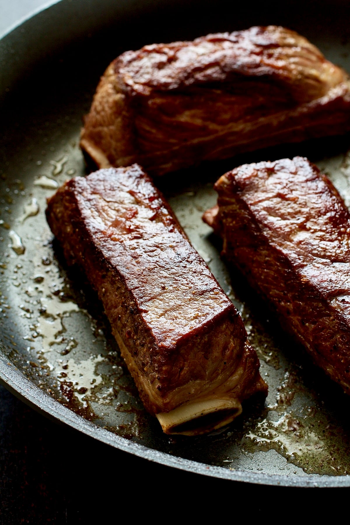 Four browned beef short ribs in nonstick skillet.