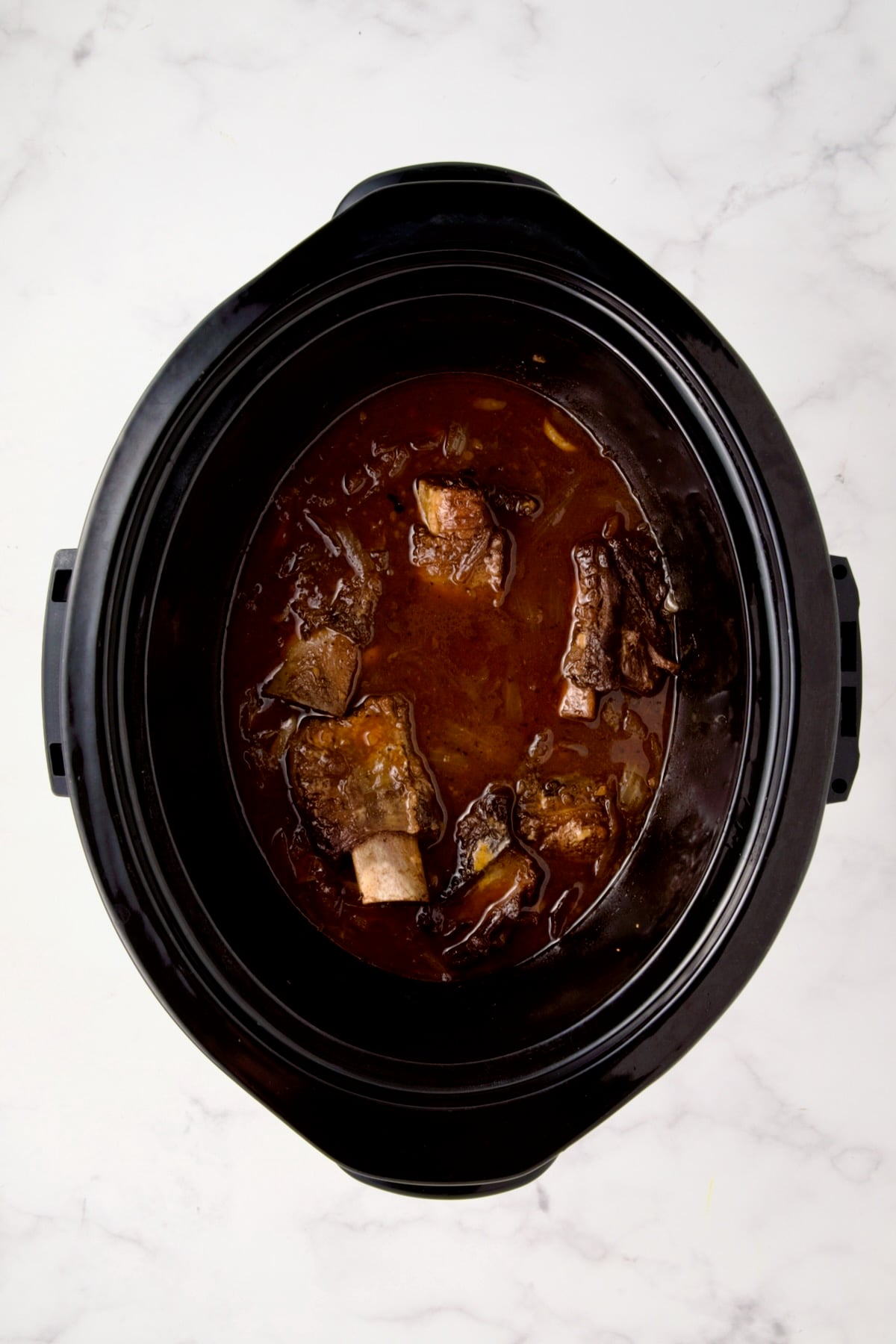 Cooked beef short ribs in slow cooker before the sauce is thickened.