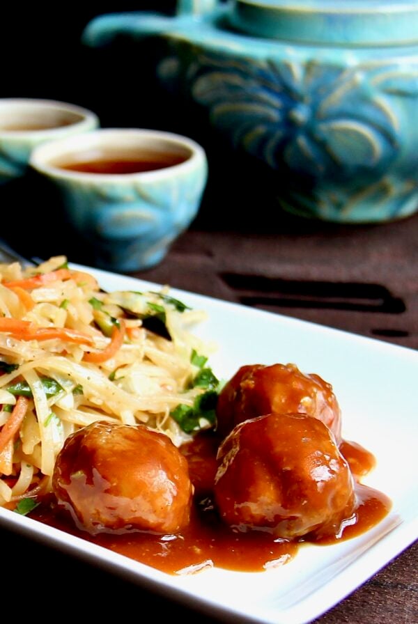 Three Asian Pork Meatballs on white plate with noodles.