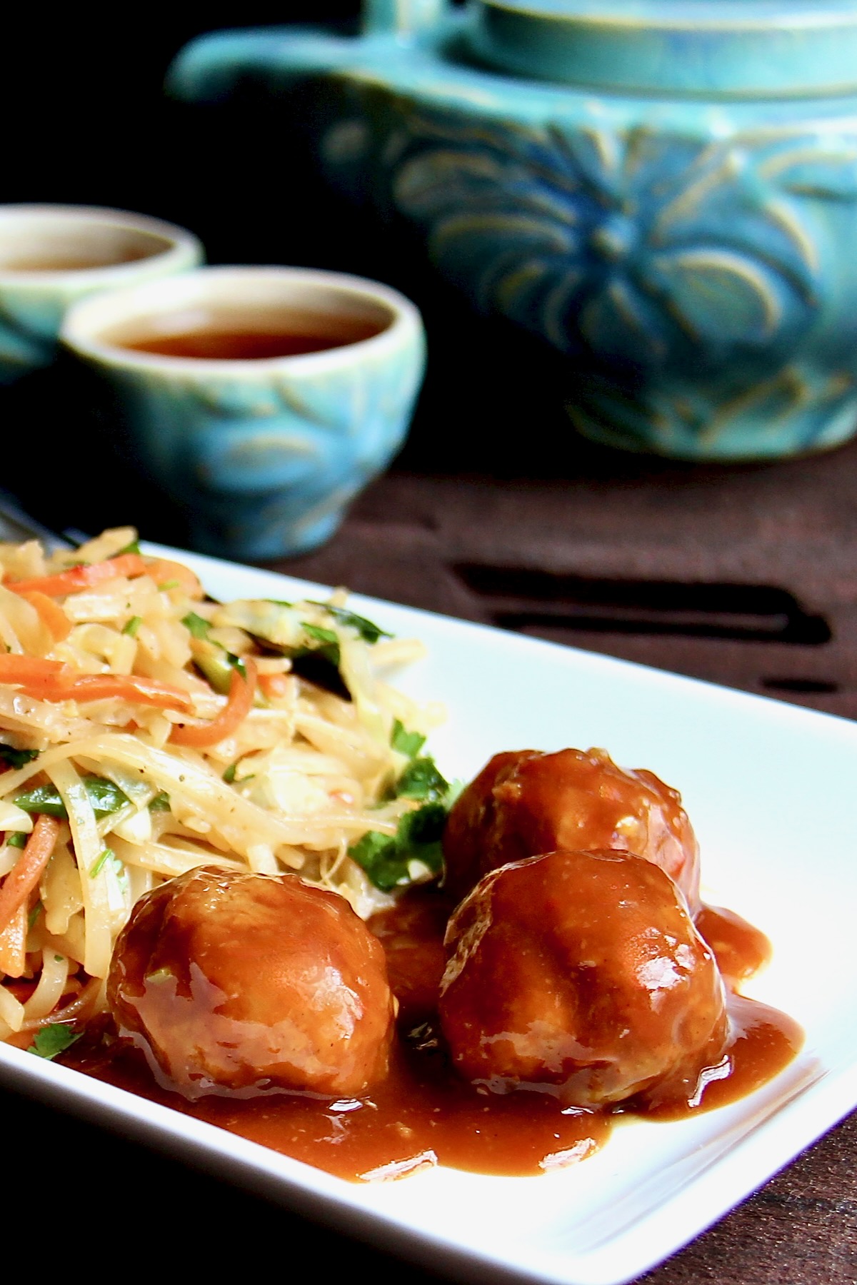 Three Asian Pork Meatballs on white plate with noodles.