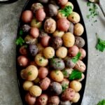 Salt Roasted Baby Potatoes on oval black patter with Sour Cream Horseradish Dip in a black bowl garnished with fresh parsley.