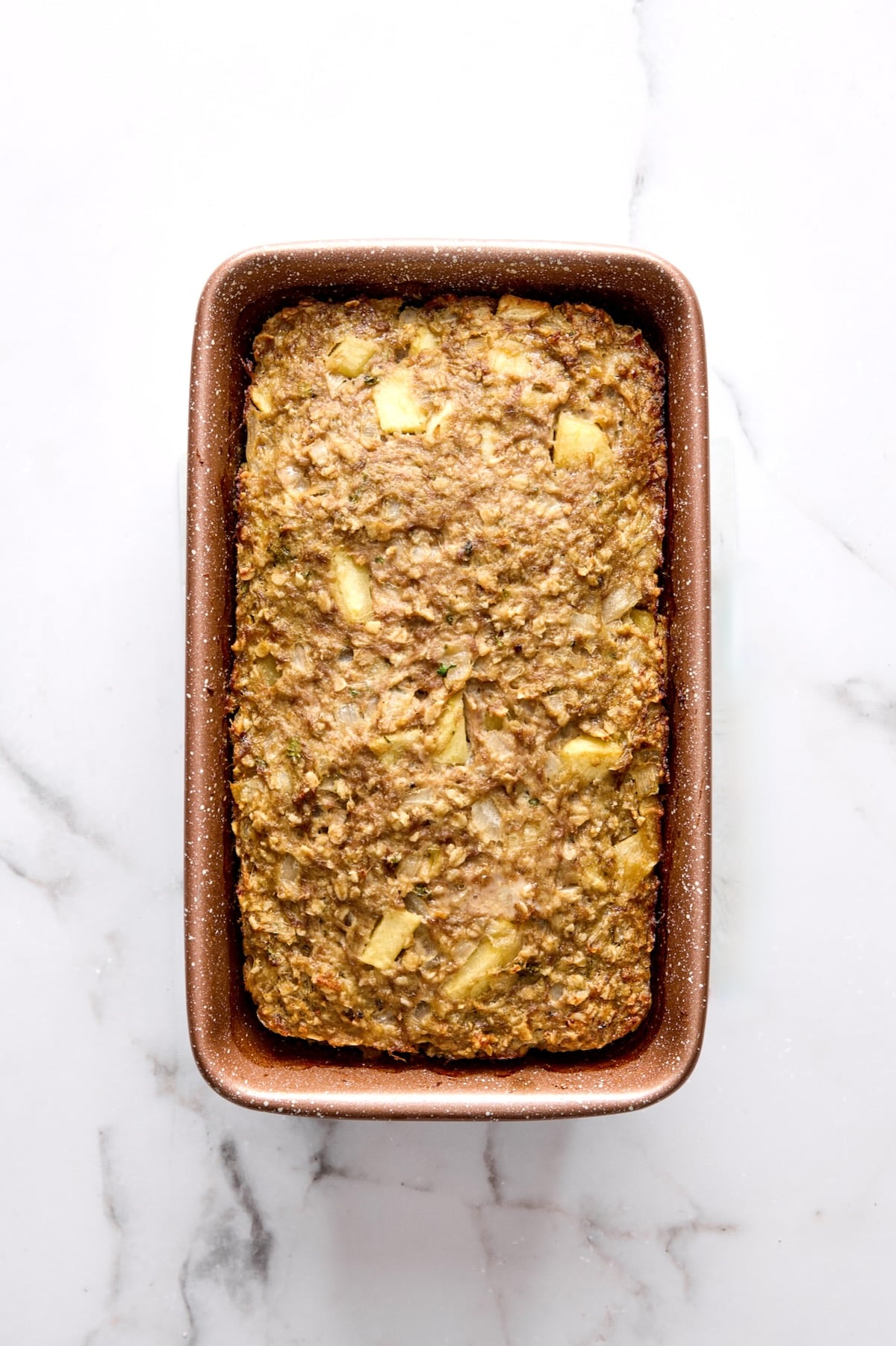 Baked meatloaf in brown loaf pan before glass is brushed over.