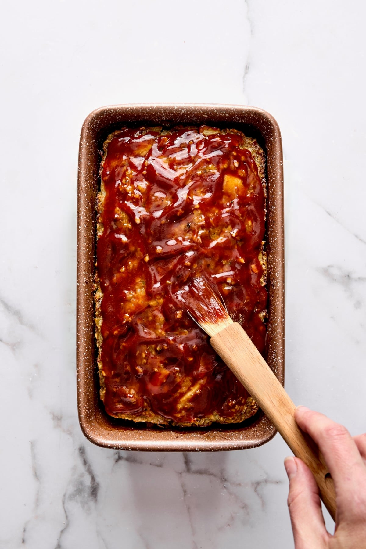 Turkey meatloaf being brushed with glaze while still in the loaf pan.