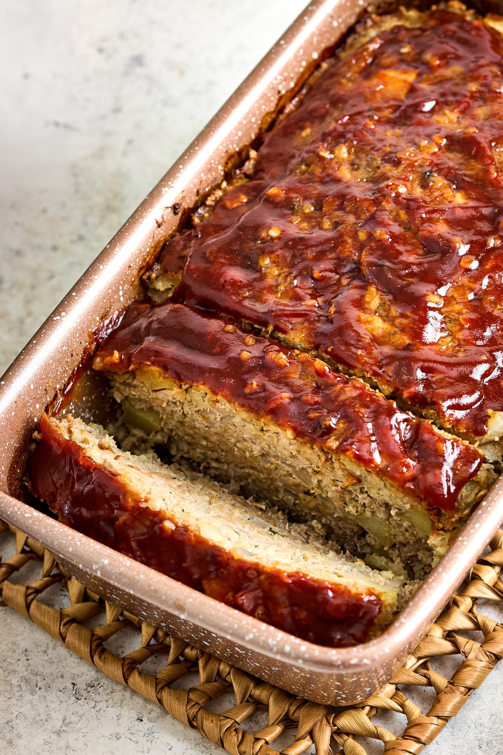 Turkey Apple Meatloaf with Balsamic Ketchup Glaze in loaf pan with two slices cut.