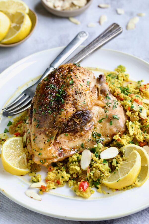 One serving of Moroccan Chicken with Jeweled Couscous on round white plate.