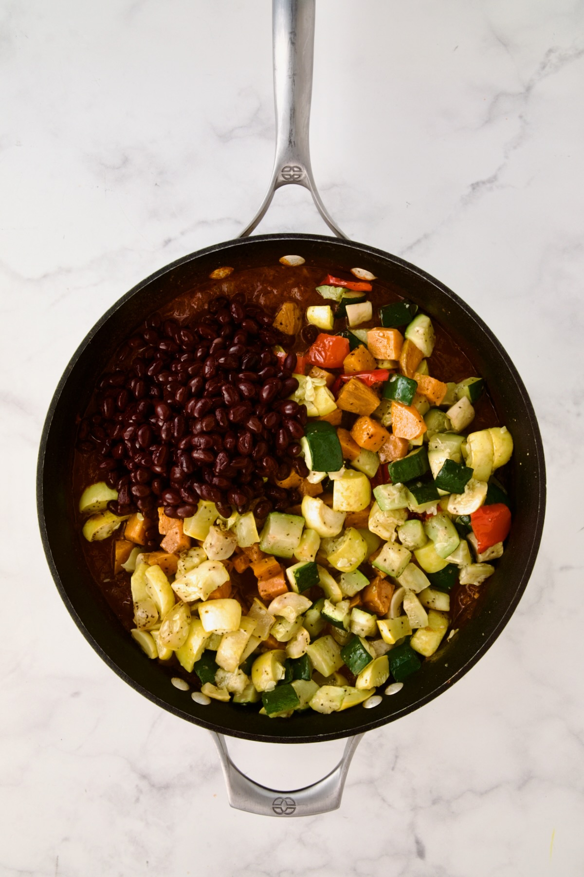 Black beans and roasted vegetables added to stew base in nonstick skillet.