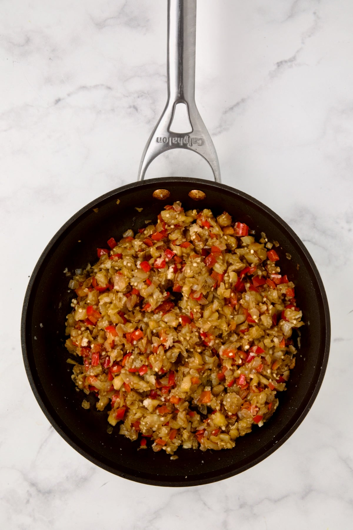 Cooked eggplant flesh, onions and red bell pepper in nonstick saute pan.