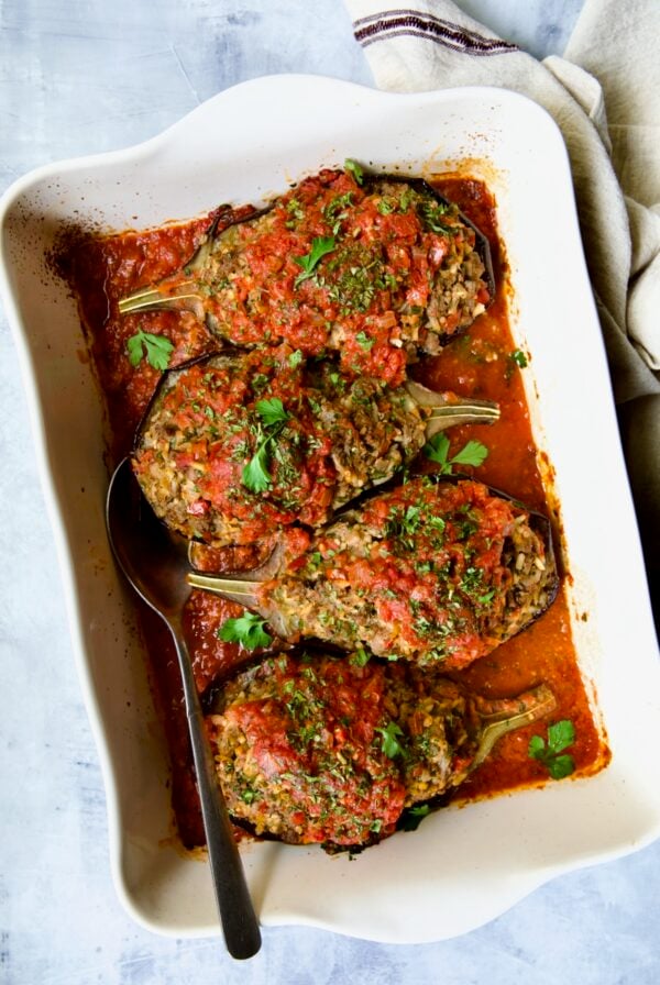 Four baked Stuffed Eggplant halves in white rectangular baking dish.