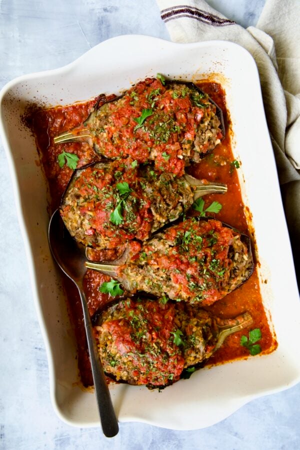 Four baked Stuffed Eggplant halves in white rectangular baking dish.
