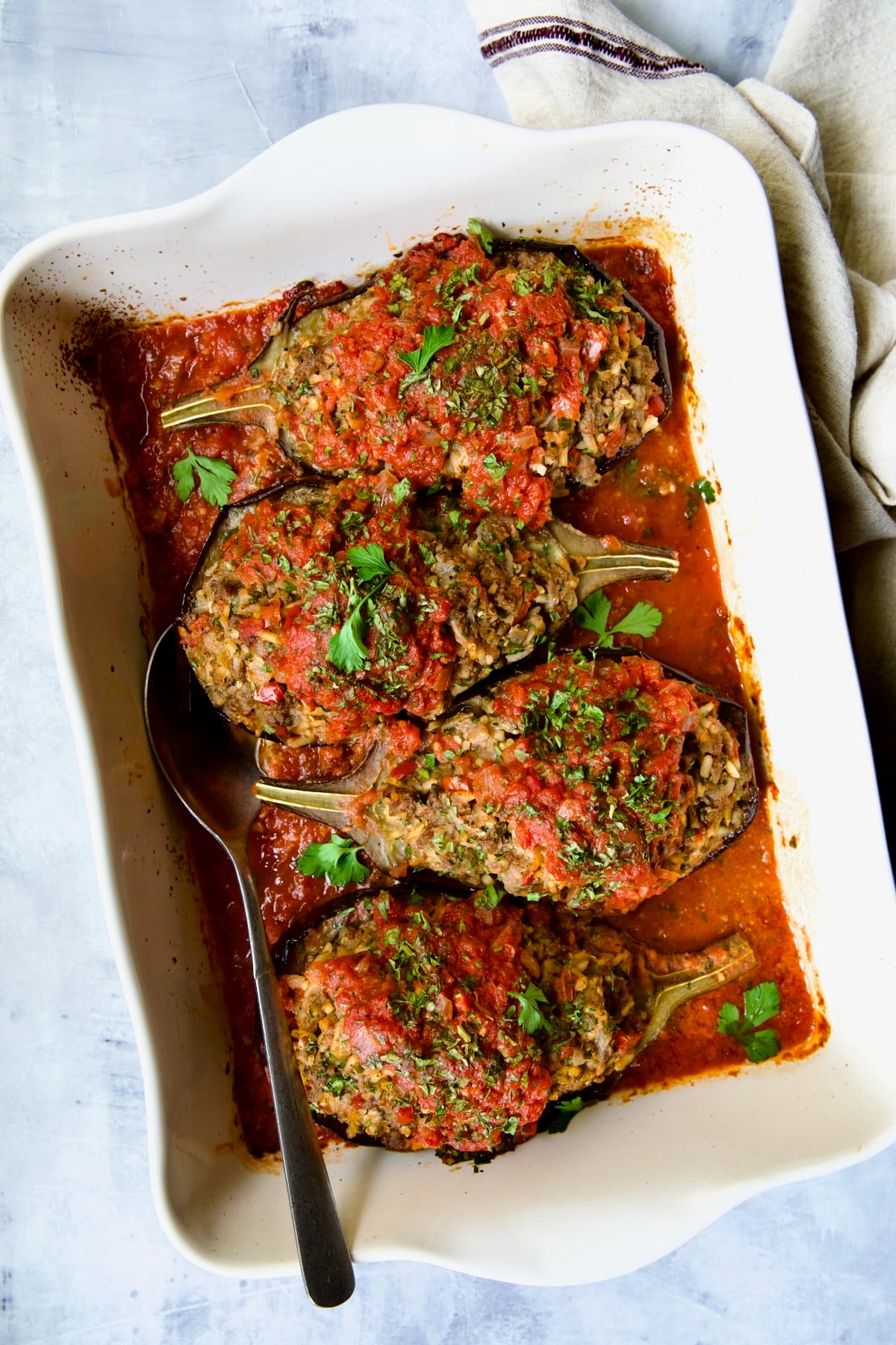 Four baked Stuffed Eggplant halves in white rectangular baking dish.