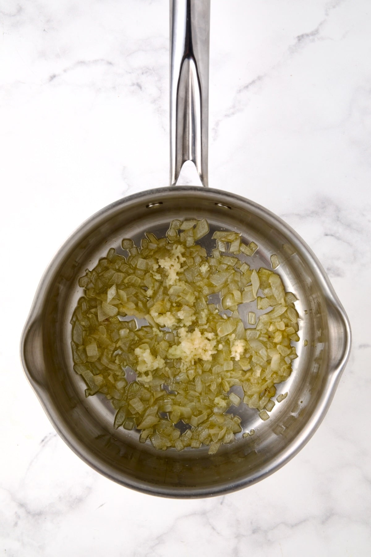 Cooked onions and garlic in stainless steel saucepan.