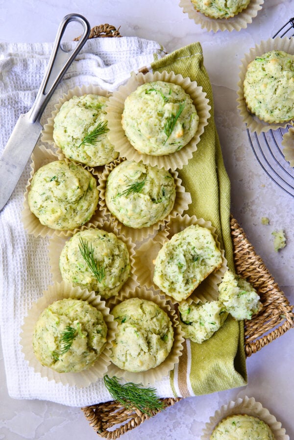 Pile of Dill Zucchini and Ricotta Muffins on square rattan basket.
