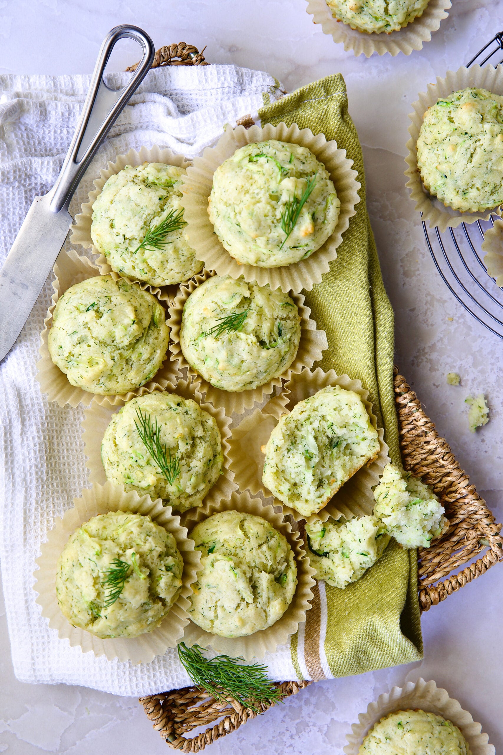 Pile of Dill Zucchini and Ricotta Muffins on square rattan basket.