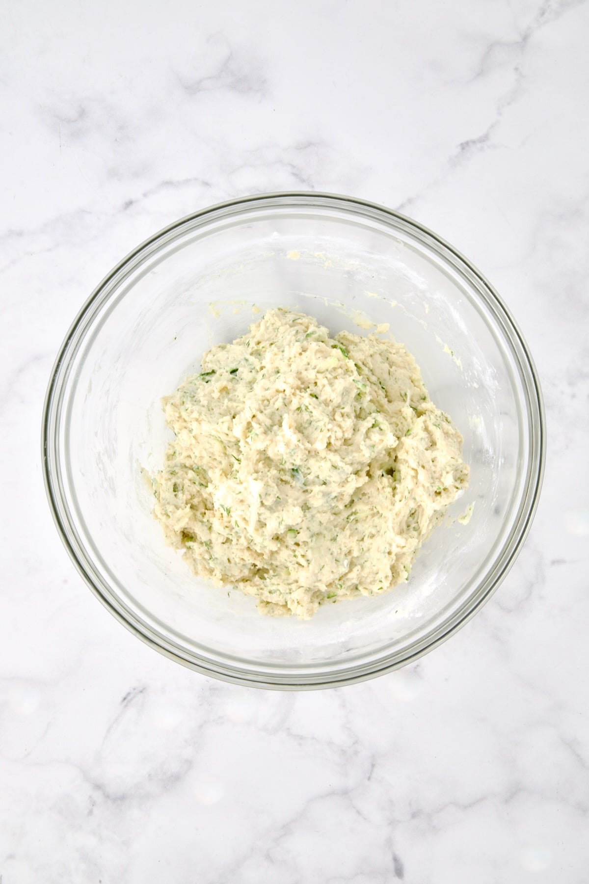 Wet and dry ingredients for muffins combined in glass bowl.