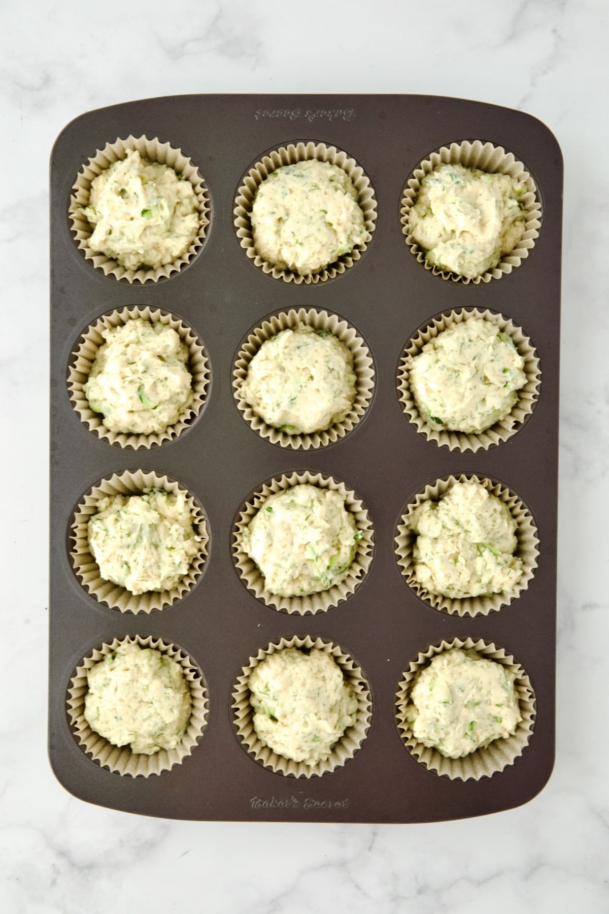 Batter for muffins divided into 12 paper-lined muffin cups.