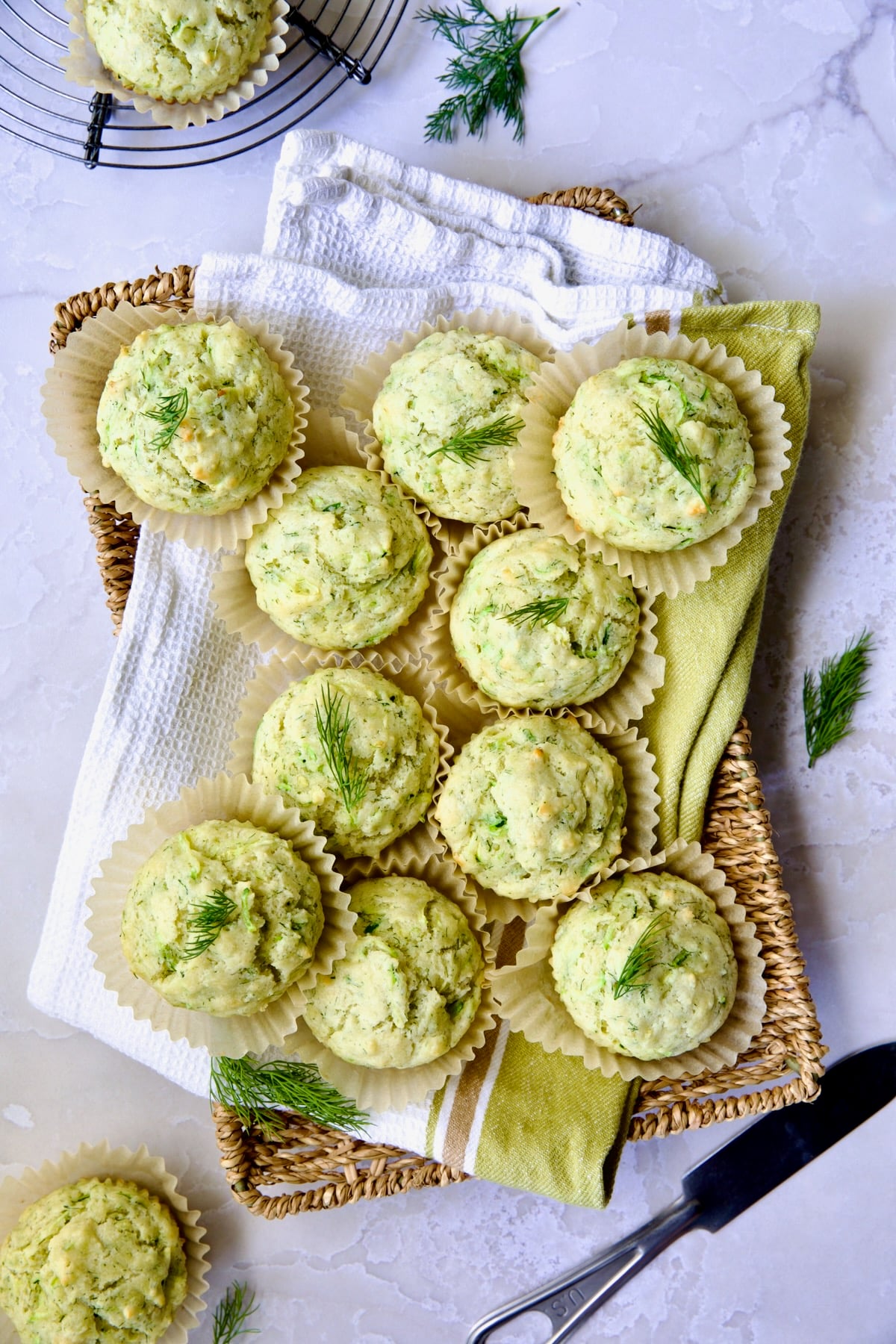 Pile of Dill Zucchini and Ricotta Muffins on square rattan basket.