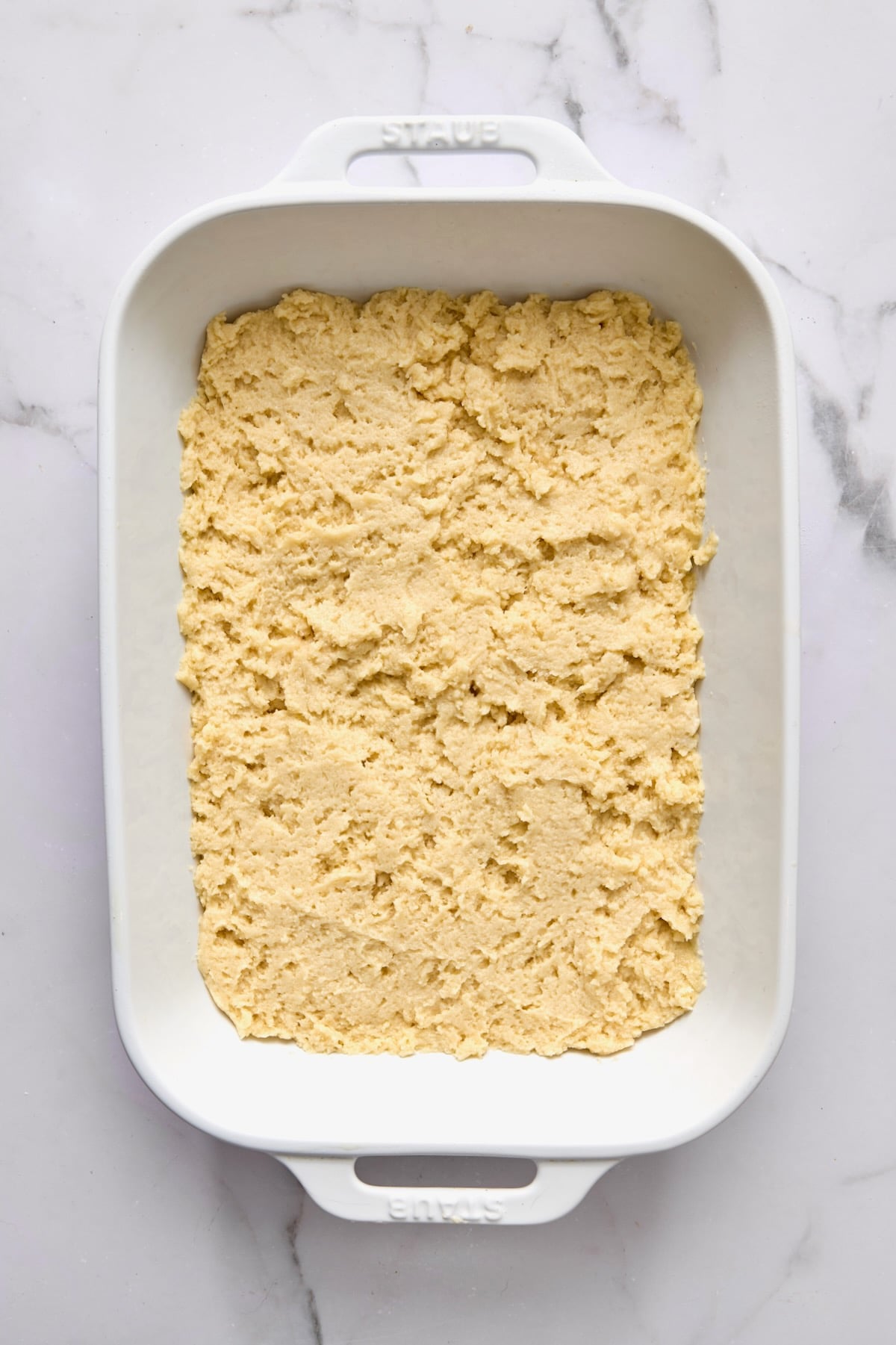 Batter for coffee cake spread into a white rectangular baking dish.