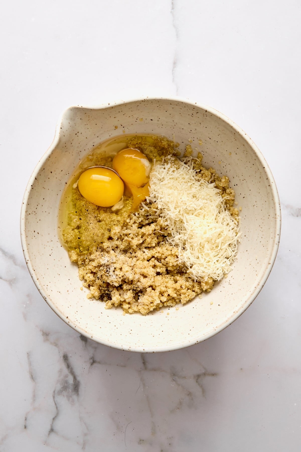 Cooked quinoa, eggs, and cheese in mixing bowl.