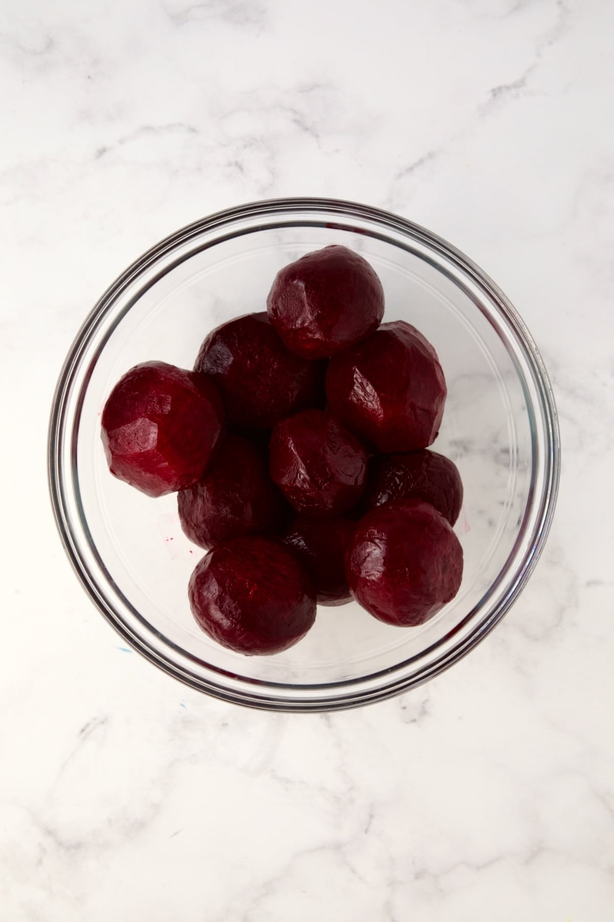 Peeled cooked beets in glass bowl.