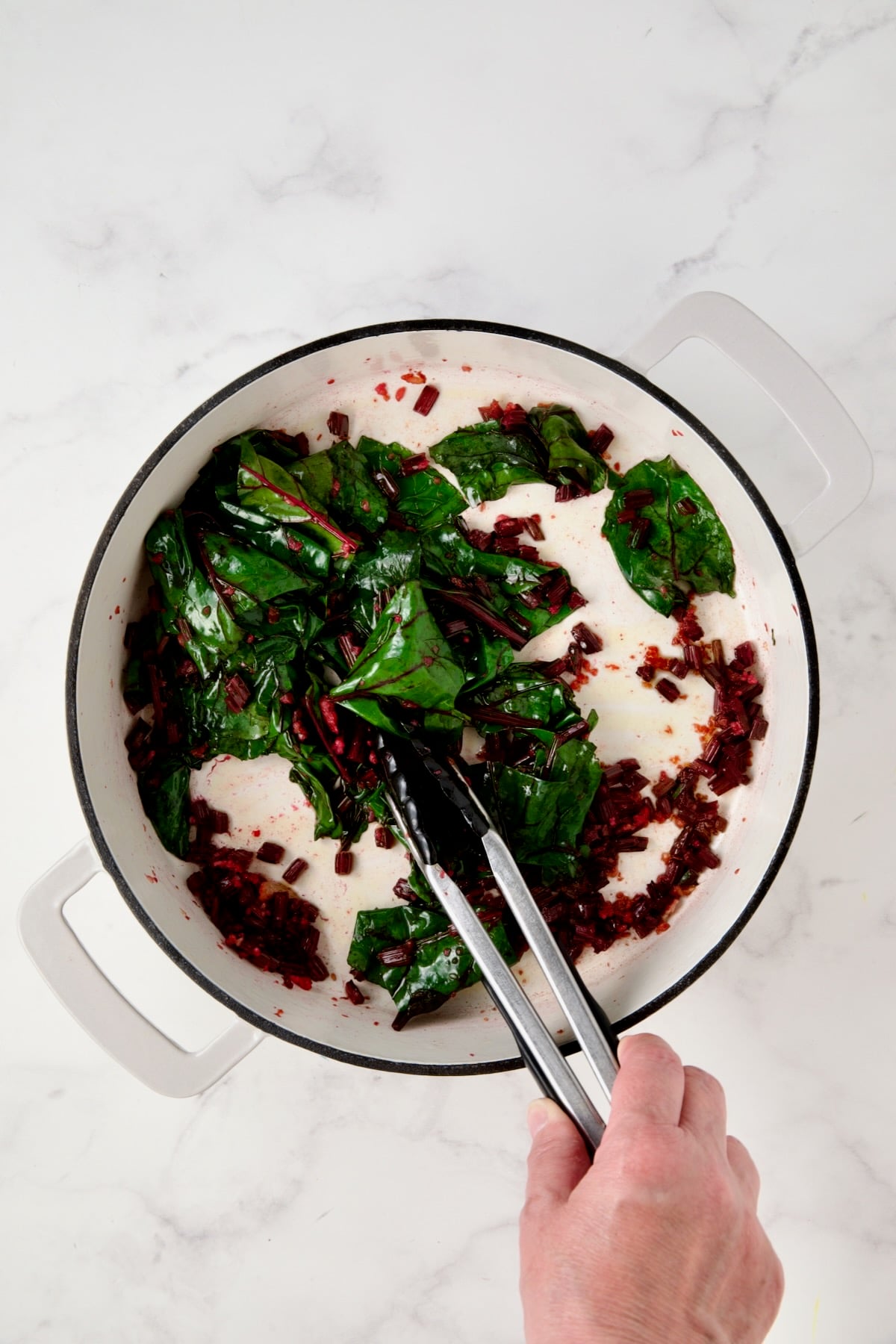 Wilted beet greens in white enamel cast iron skillet.