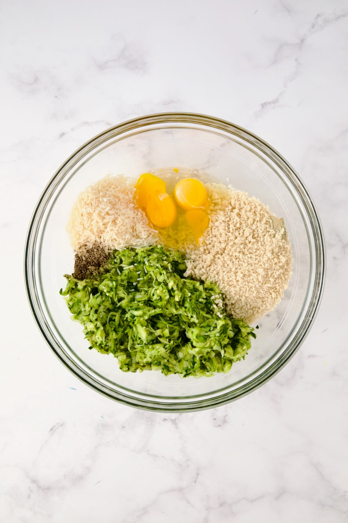 Ingredients for the zucchini crust in glass bowl before being mixed together.