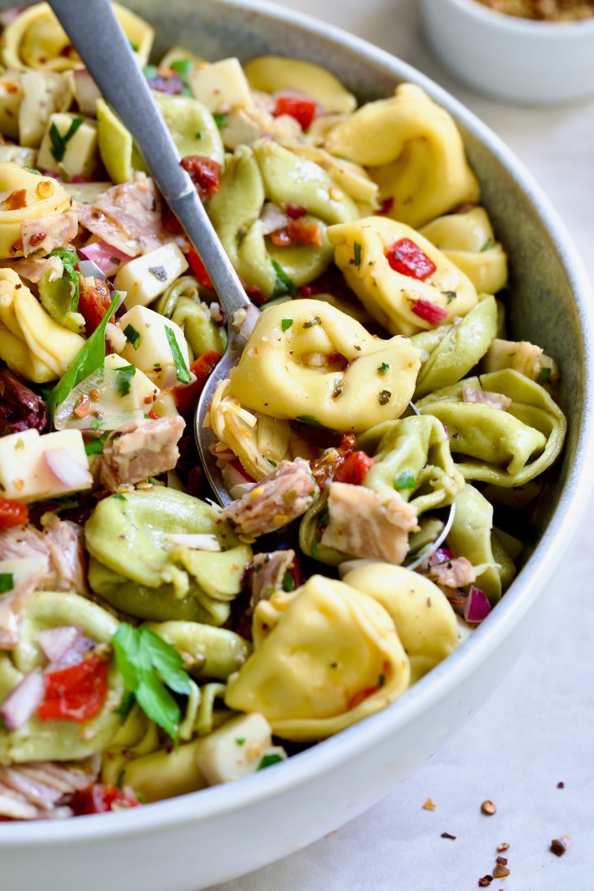 Antipasto Tortellini Salad in serving bowl with serving spoon scooping some up.