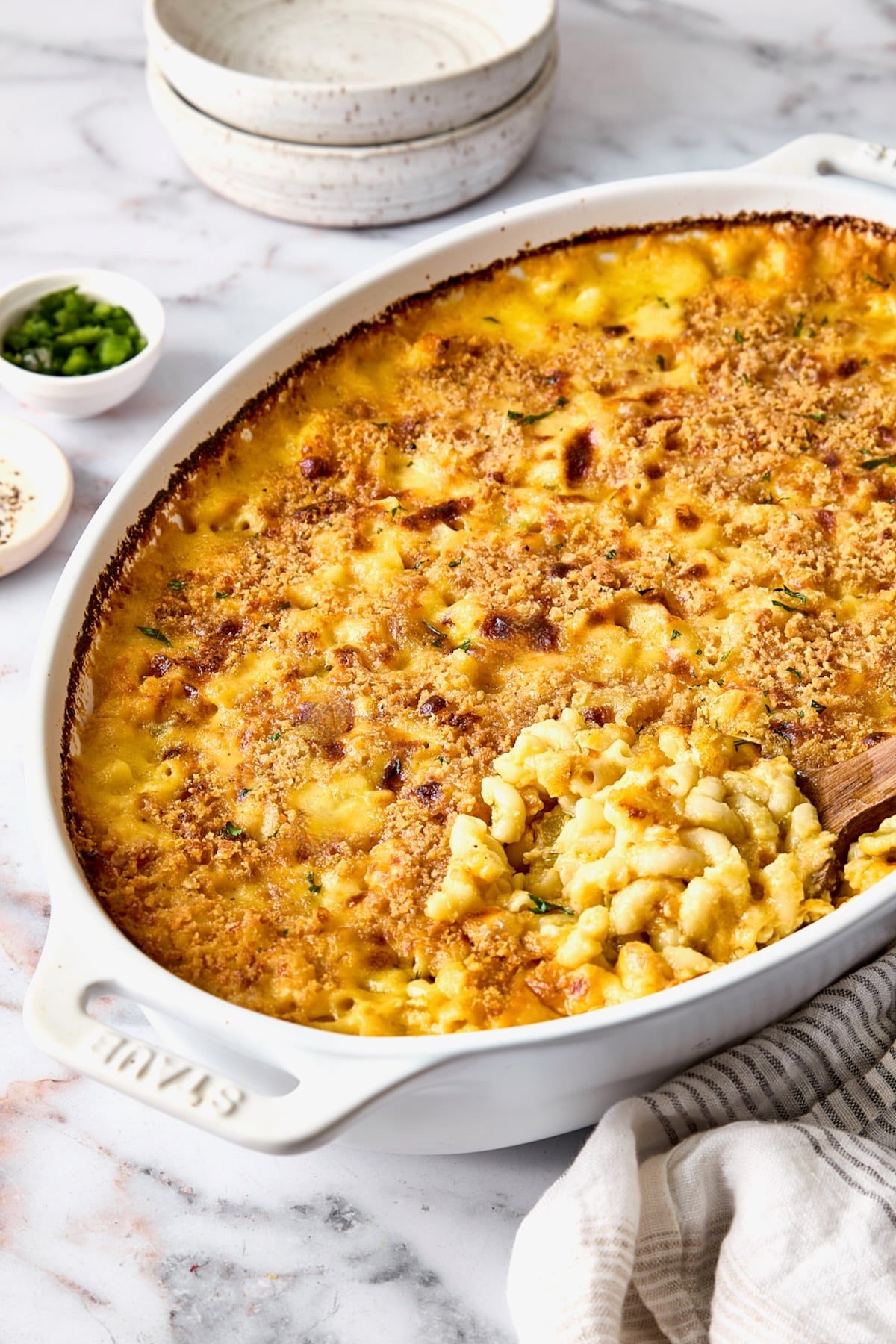 Hatch Green Chili Mac and Cheese in oval baking dish with some being scooped out with wooden spoon.