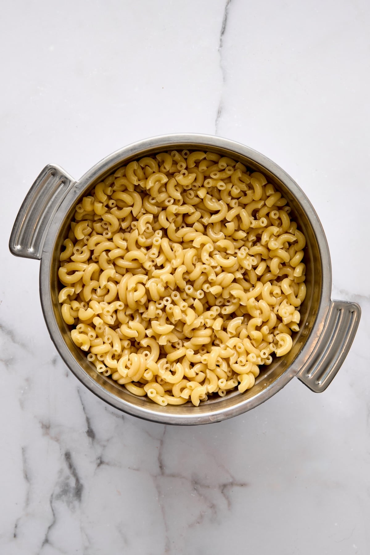 Cooked elbow macaroni in stainless steel pot.