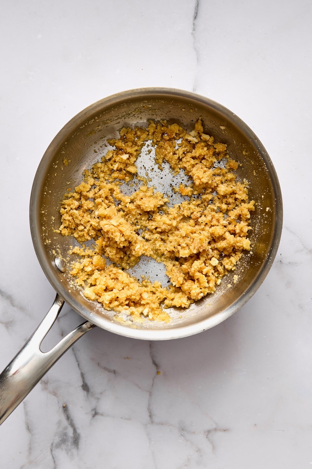 Buttery breadcrumbs in stainless steel skillet.