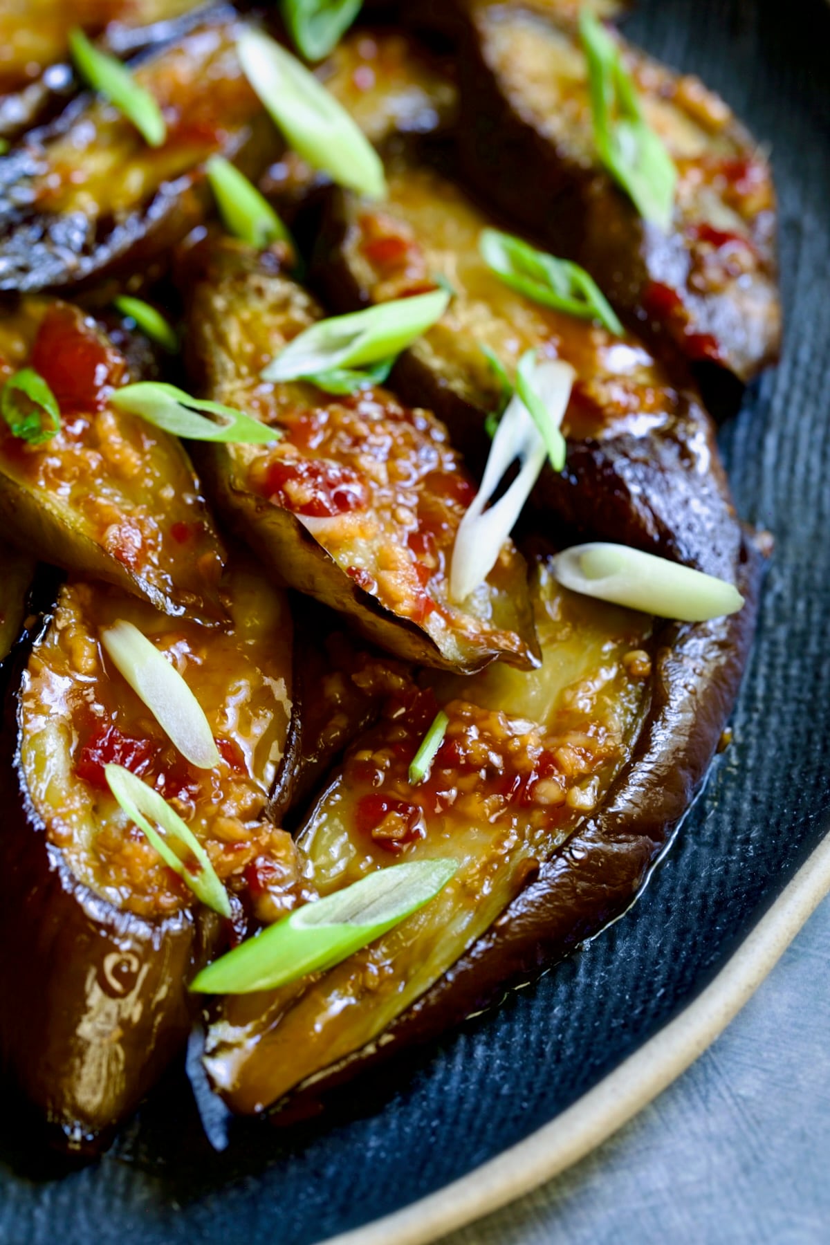 Thai Sweet Chili Eggplant on blue oval plate garnished with scallions.