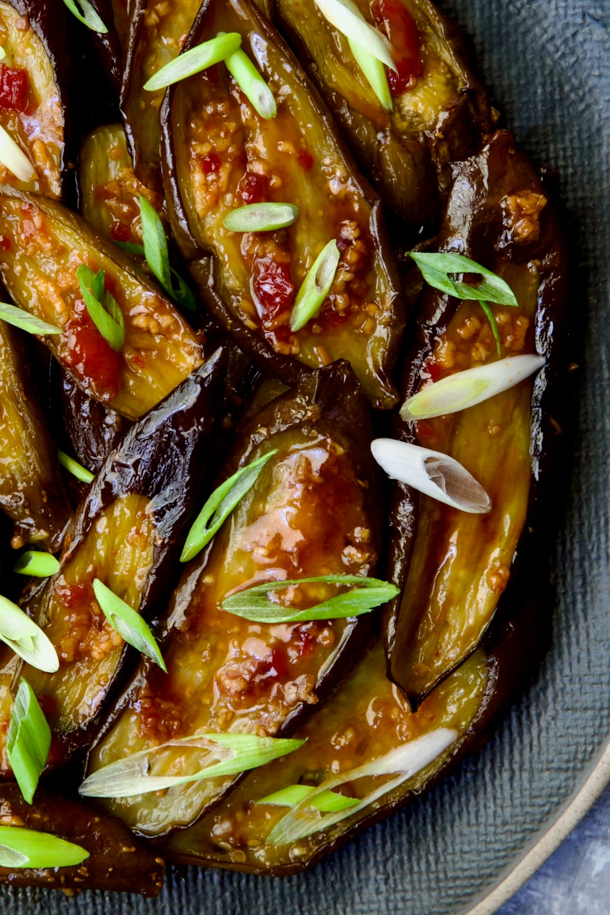 Thai Sweet Chili Eggplant on blue oval plate garnished with scallions.