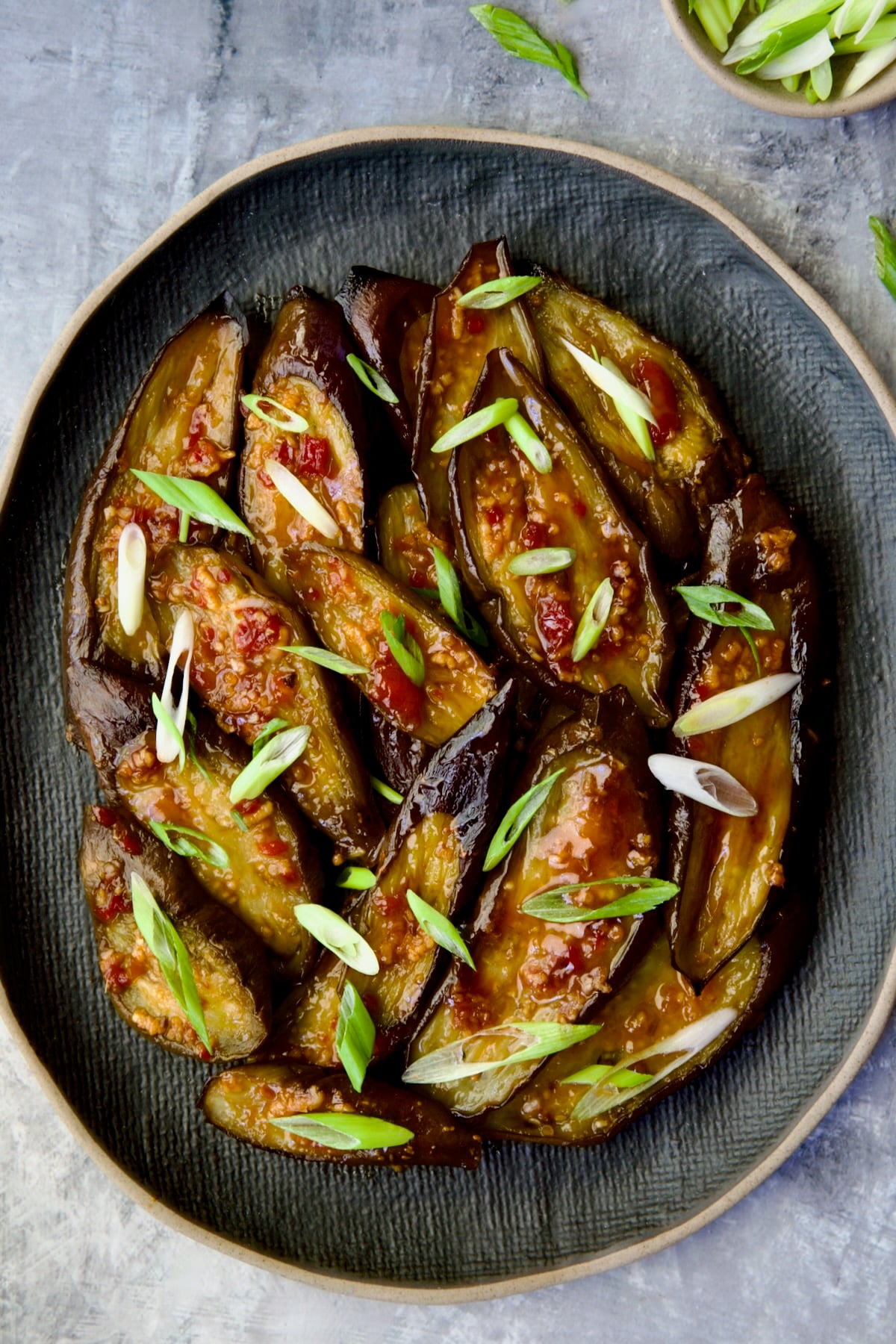 Thai Sweet Chili Eggplant on blue oval plate garnished with scallions.