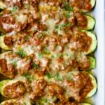 Six baked Chorizo-Stuffed Zucchini in white rectangular baking dish.