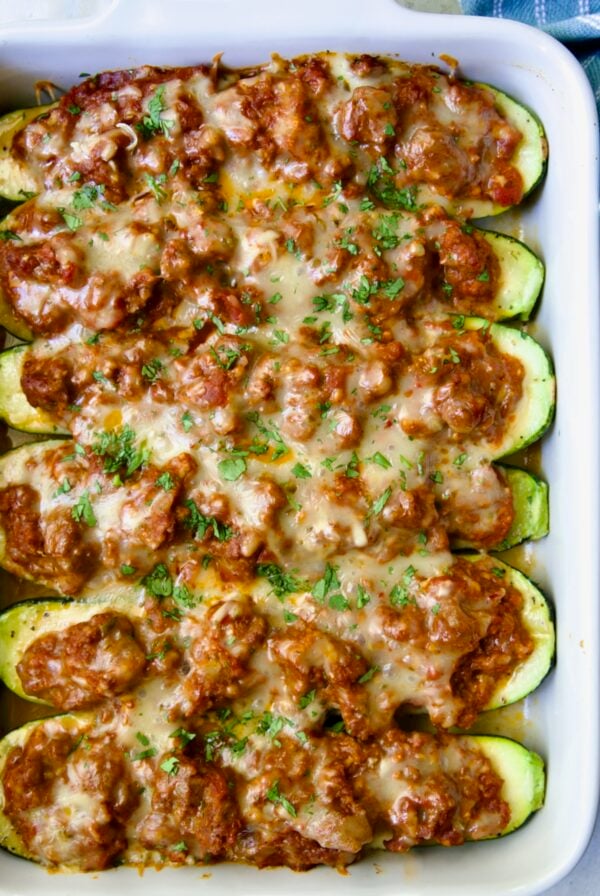 Six baked Chorizo-Stuffed Zucchini in white rectangular baking dish.