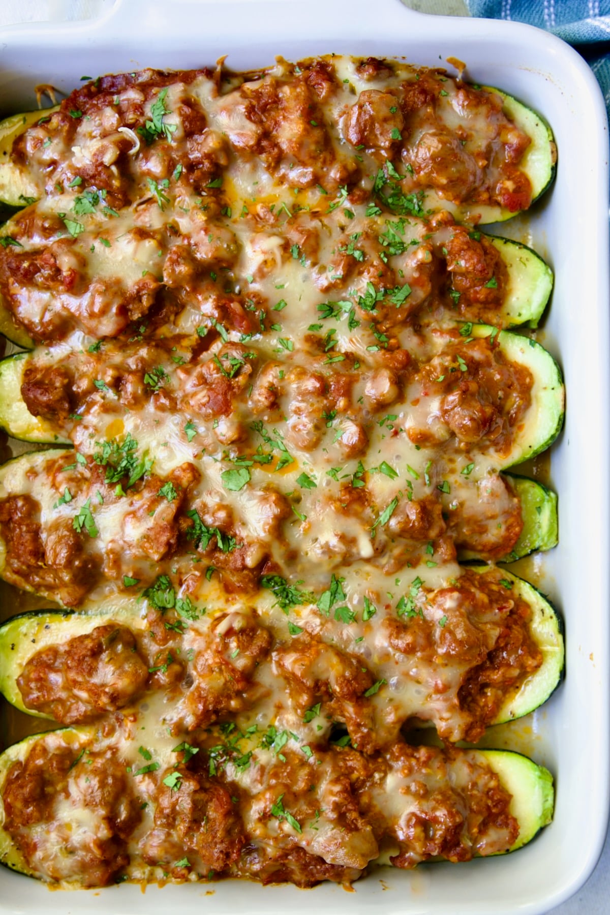 Six baked Chorizo-Stuffed Zucchini in white rectangular baking dish.