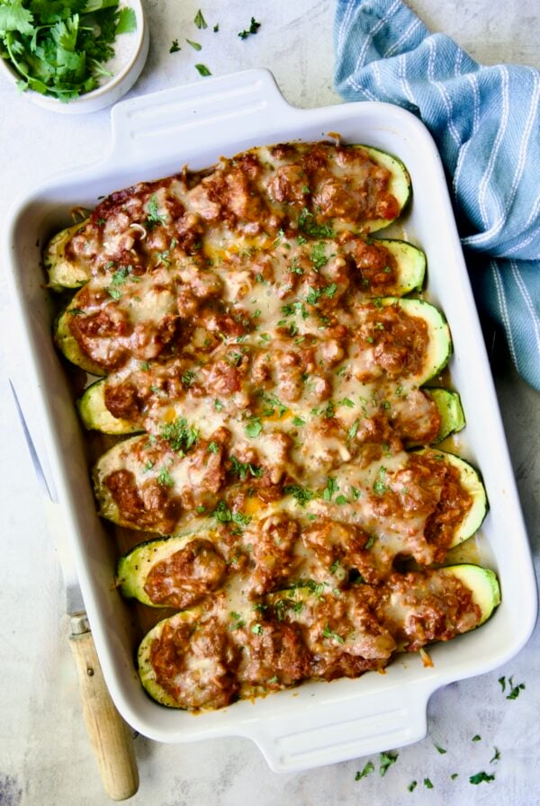 Six baked Chorizo-Stuffed Zucchini in white rectangular baking dish.